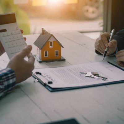 Real estate professionals offer their clients contracts to discuss home purchases, insurance or real estate loans. Home sales agents sit at the office with new home buyers in the office.
