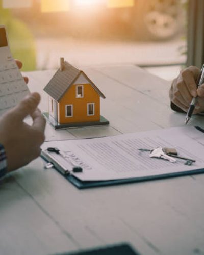 Real estate professionals offer their clients contracts to discuss home purchases, insurance or real estate loans. Home sales agents sit at the office with new home buyers in the office.
